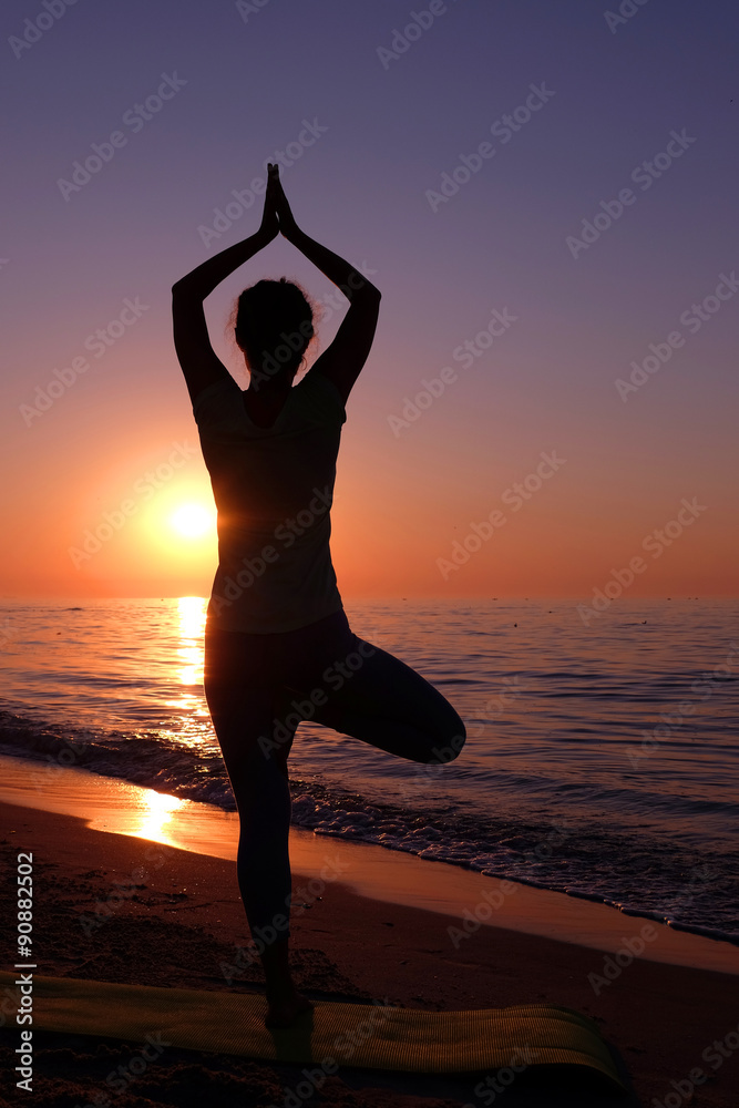 Young healthy woman practicing yoga on the beach at sunset - obrazy, fototapety, plakaty 