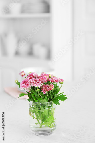 Beautiful flowers in vase on table, on light background