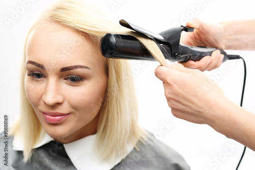 Lokówka.Kobieta w salonie fryzjerskim, fryzjer kręci włosy na lokówkę.
