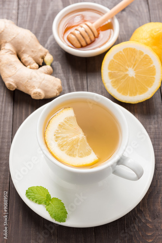 Cup of ginger tea with lemon and honey on wooden background