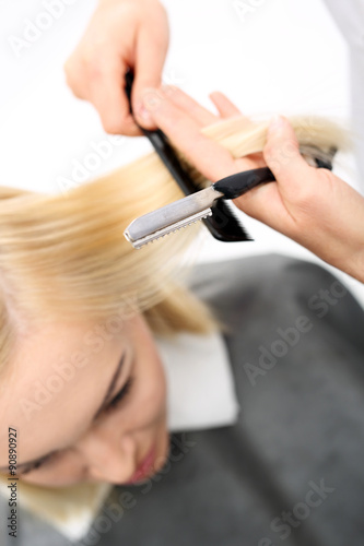 Strzyżenie włosów nożem chińskim. Fryzjer strzyże kobietę nożem chińskim w salonie fryzjerskim