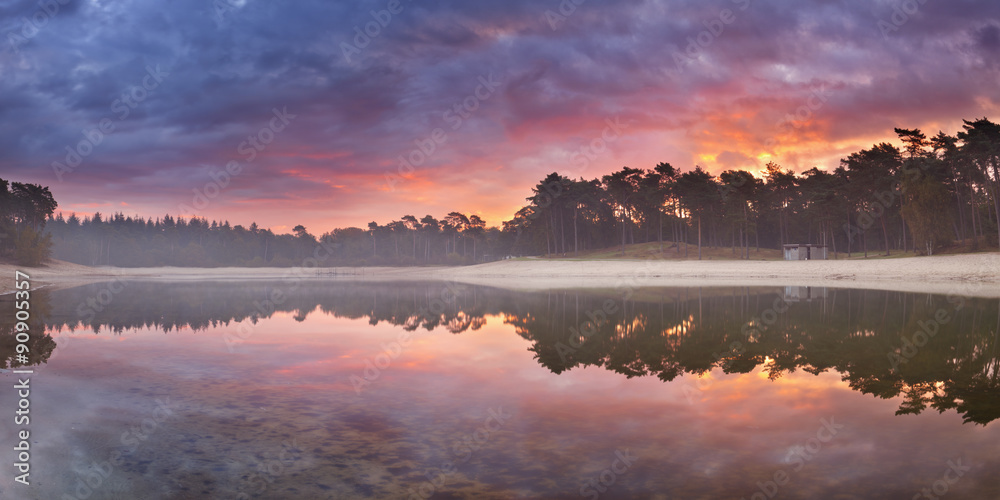 Reflections of sunrise at a quiet lake in The Netherlands