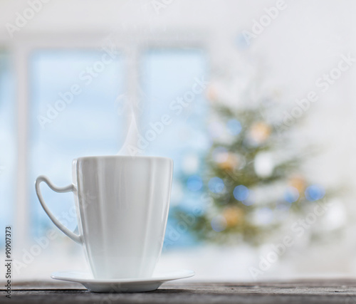white cup on background Christmas fir and window