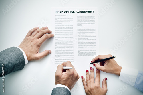 young man an woman signing a prenuptial agreement photo