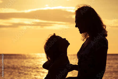 Mother and son playing on the beach at the sunset time.