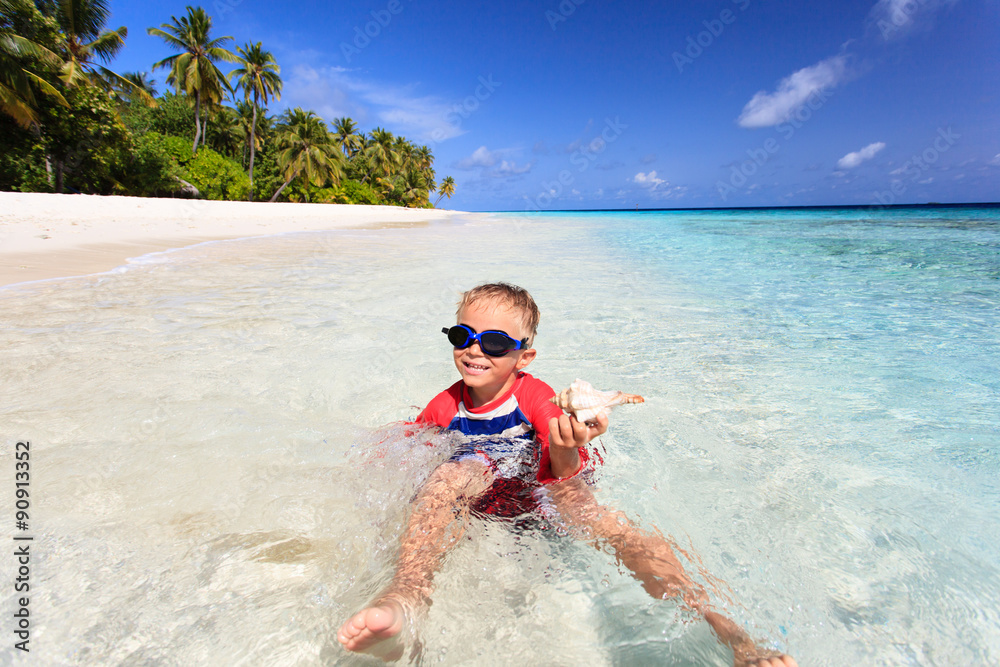 little boy swimming found shell on beach