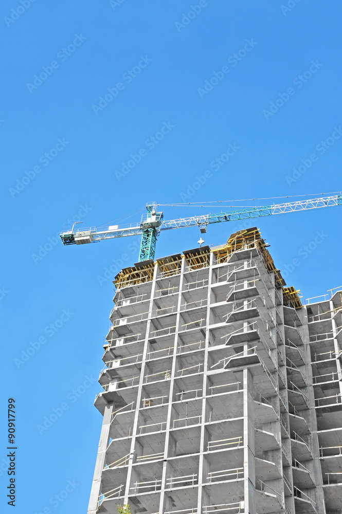 Crane and building construction site against blue sky Crane and building construction site against blue sky