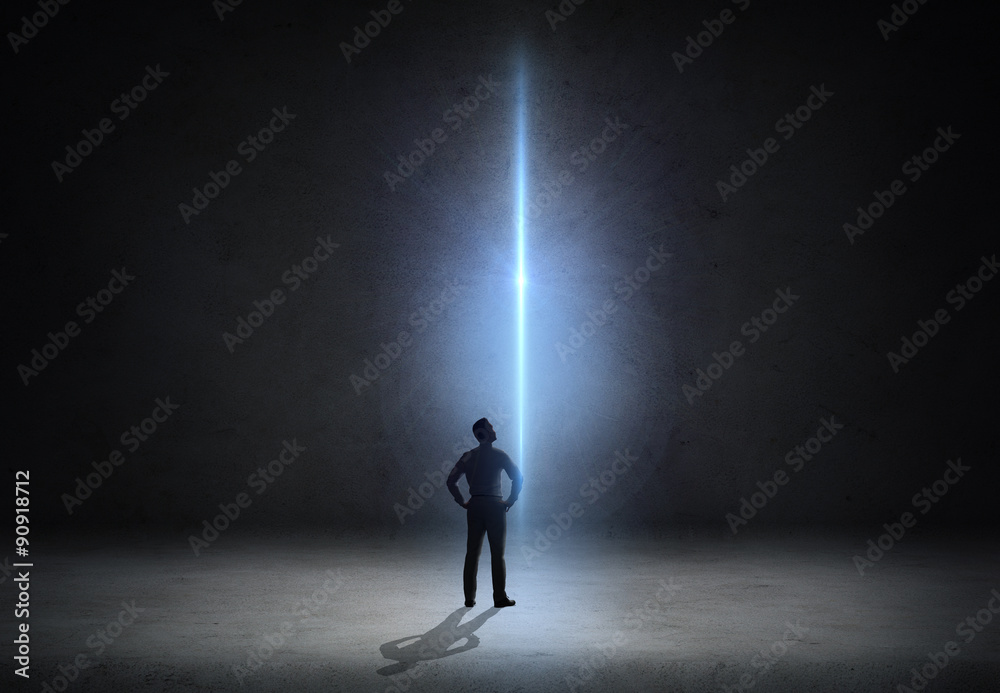 businessman looking at ray of light over dark room businessman looking at ray of light over dark room