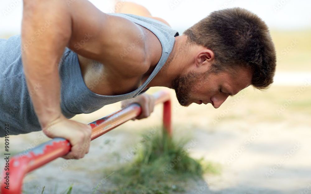 young man exercising on horizontal bar outdoors young man exercising on horizontal bar outdoors