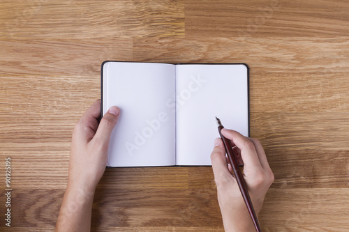 Mano con pluma escribiendo en libreta en blanco photo