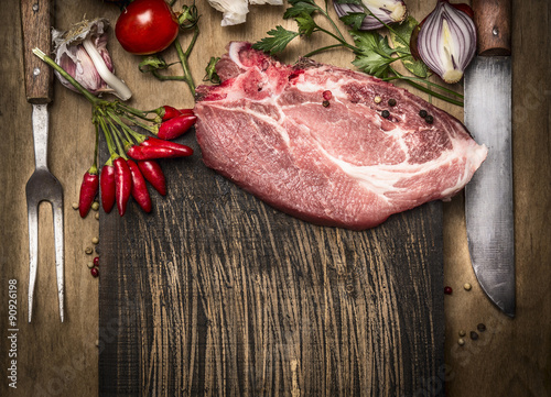 Pork meat chops with fresh herbs and spices for cooking, fork and knife on rustic wooden background, top view photo