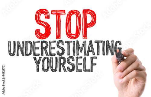 Hand with marker writing the word Stop Underestimating Yourself photo