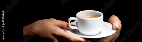 Hands holding cup of coffee on black background