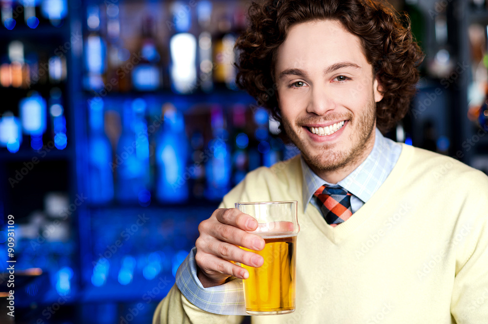 Smiling young man holding a glass of beer