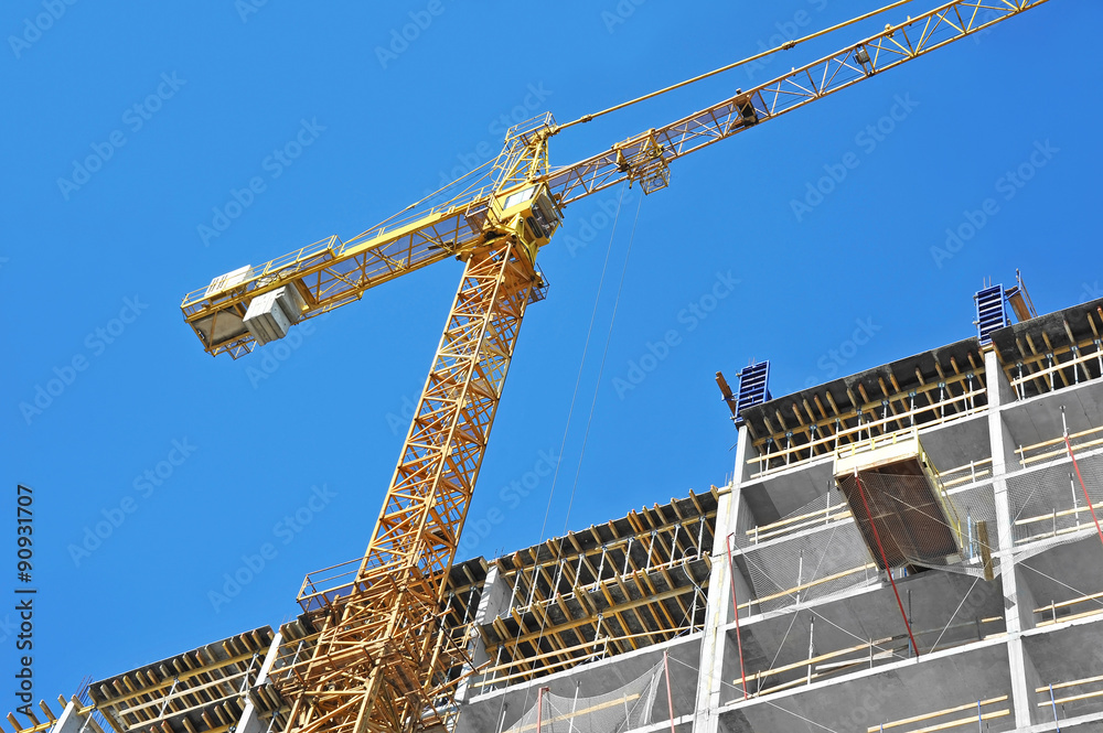 Crane and building construction site against blue sky