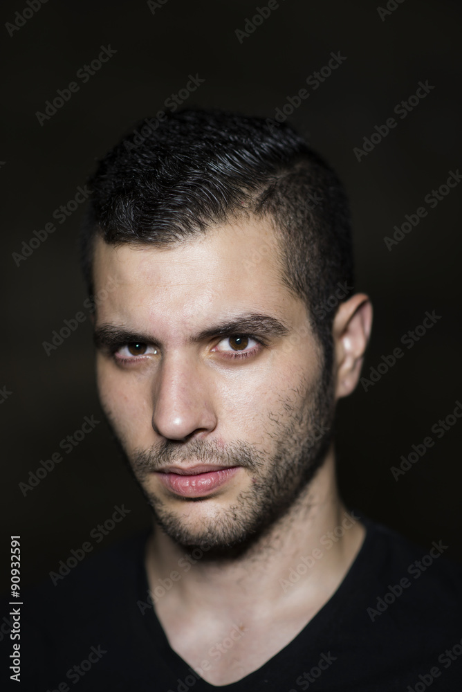 Young 20s modern man posing on dirty wall with ambient ligh. Young 20s modern man posing on dirty wall with ambient ligh.