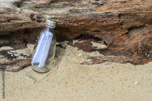 message in a bottle on wood and sand background