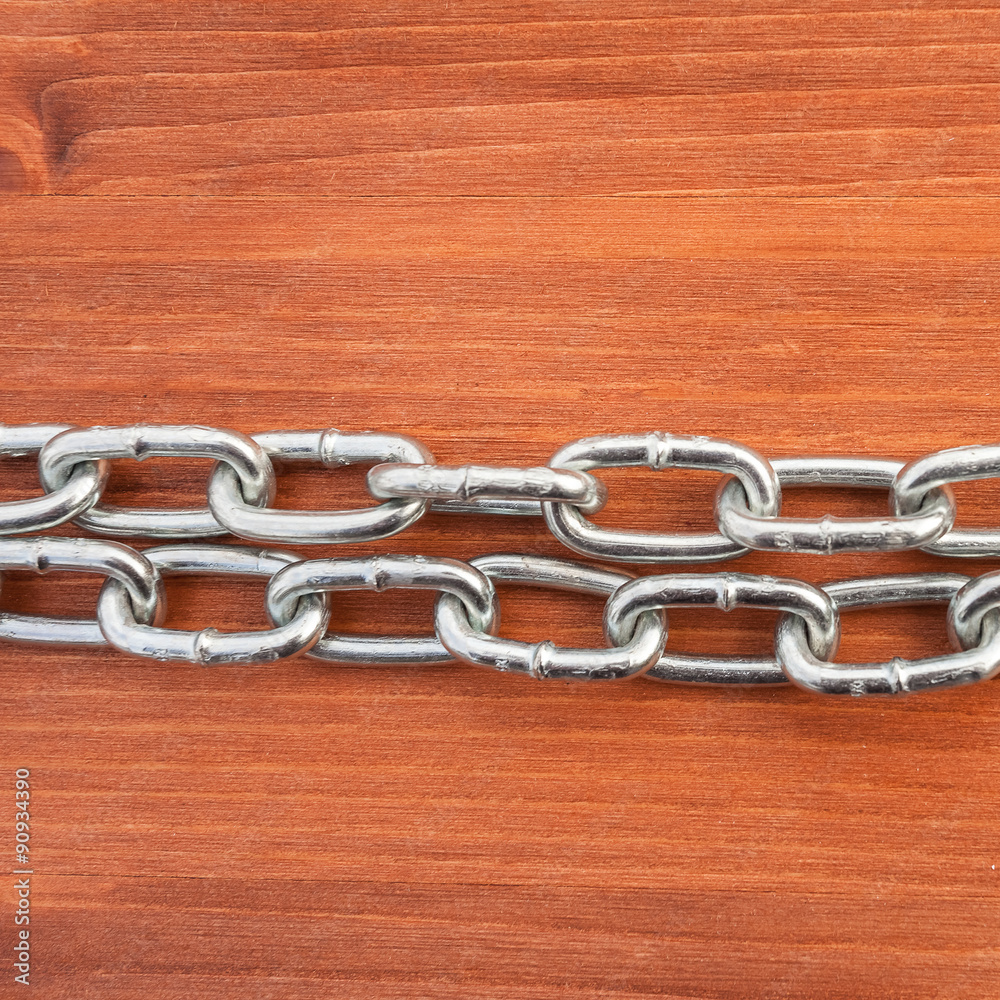 Metal chain links on wooden background Metal chain links on wooden background