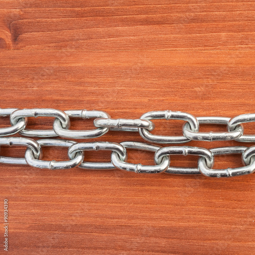 Metal chain links on wooden background