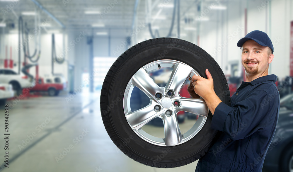 Car mechanic with a tire . Car mechanic with a tire .