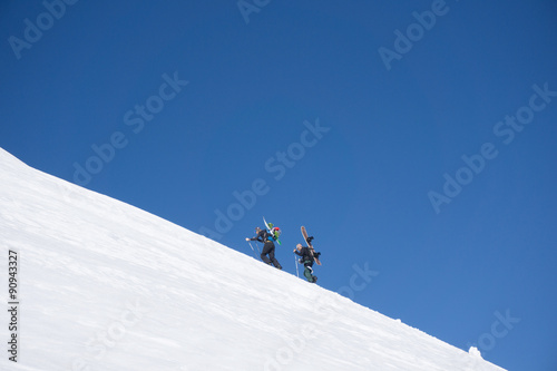 Fotografie, Obraz Snowboarders walking uphill for freeride