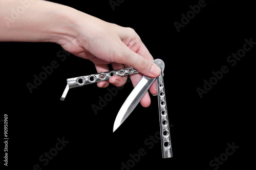 Butterfly knife (balisong) in female hand on a black background