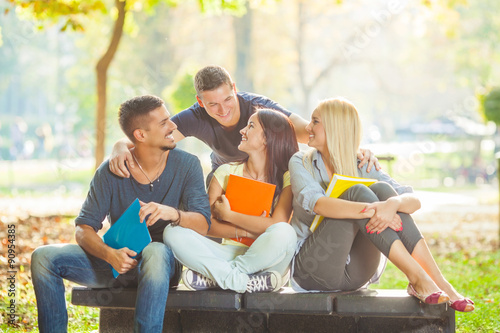 Tableau sur toile Group of cheerful college students sitting together in a university campus