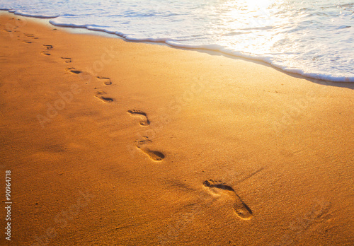 beach, wave and footprints at sunset time