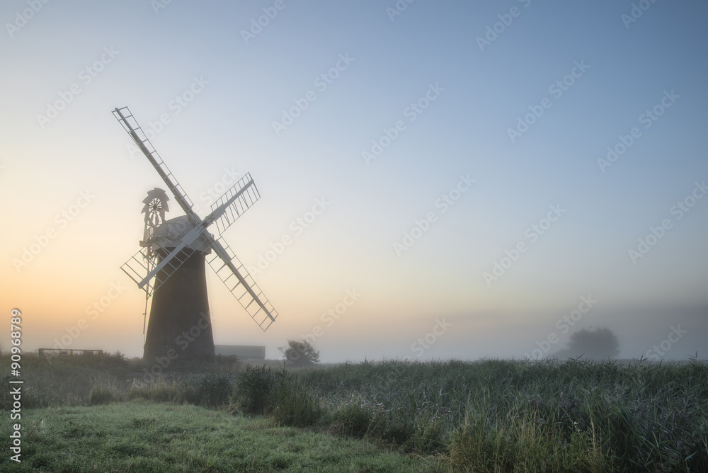 Windmill in stunning landscape on beautiful Summer dawn