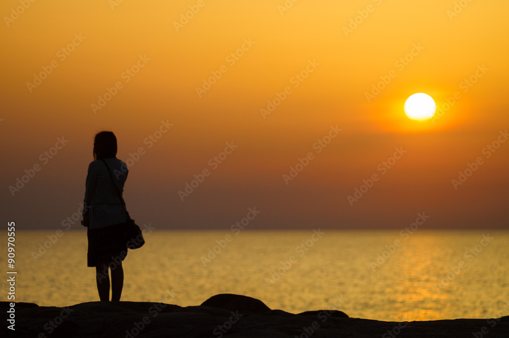 Sunset silhouette of young girl waiting for someone on seaside