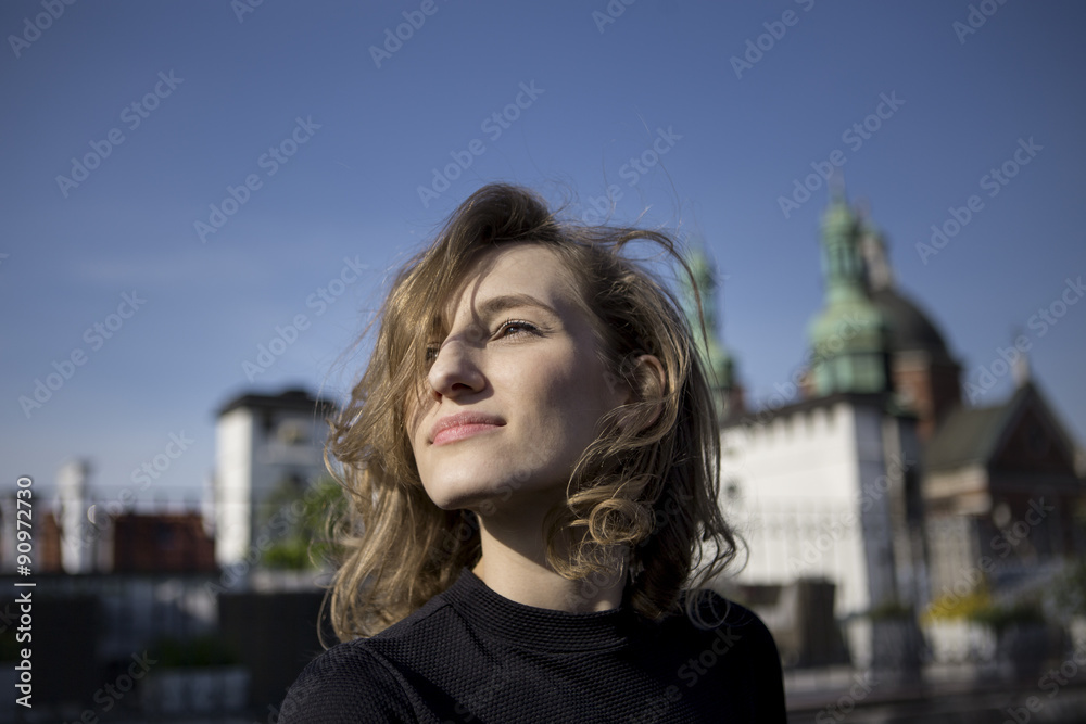 Beautiful woman with a .happy expression on her face looking right with a view of old town in the background
