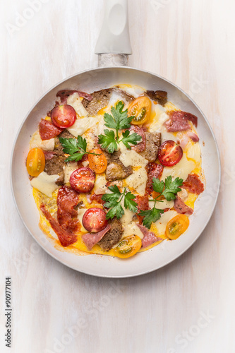 Egg omelette in white frypan with tomatoes,bread, cheese and sausage