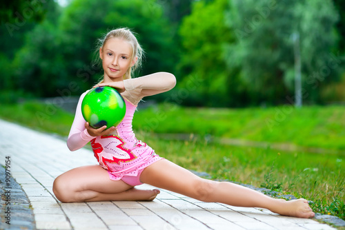 Obraz na plátně outdoor portrait of young cute little girl gymnast training with