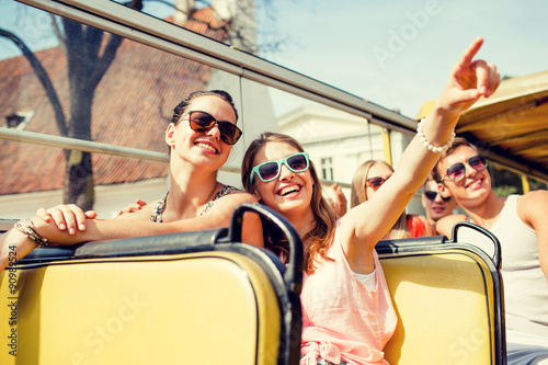 group of smiling friends traveling by tour bus