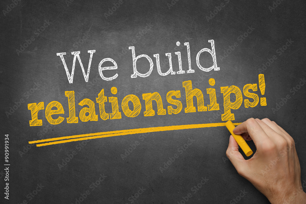 hand writes with chalk on blackboard We build relationships! StockFoto Adobe Stock