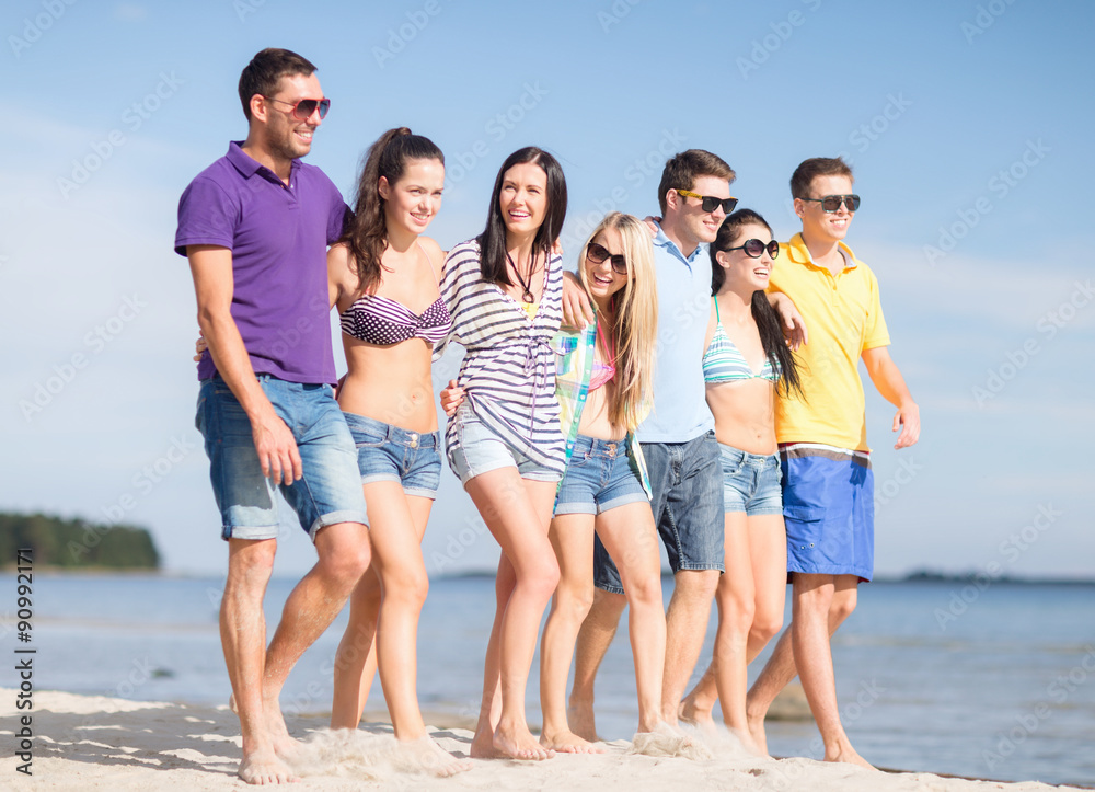 group of happy friends walking along beach group of happy friends walking along beach
