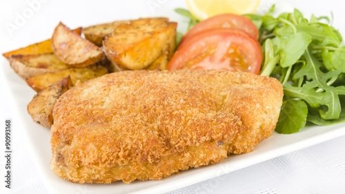 Wiener Schnitzel - Veal steak breaded and fried in butter served with salad, potato wedges and a lemon slice.