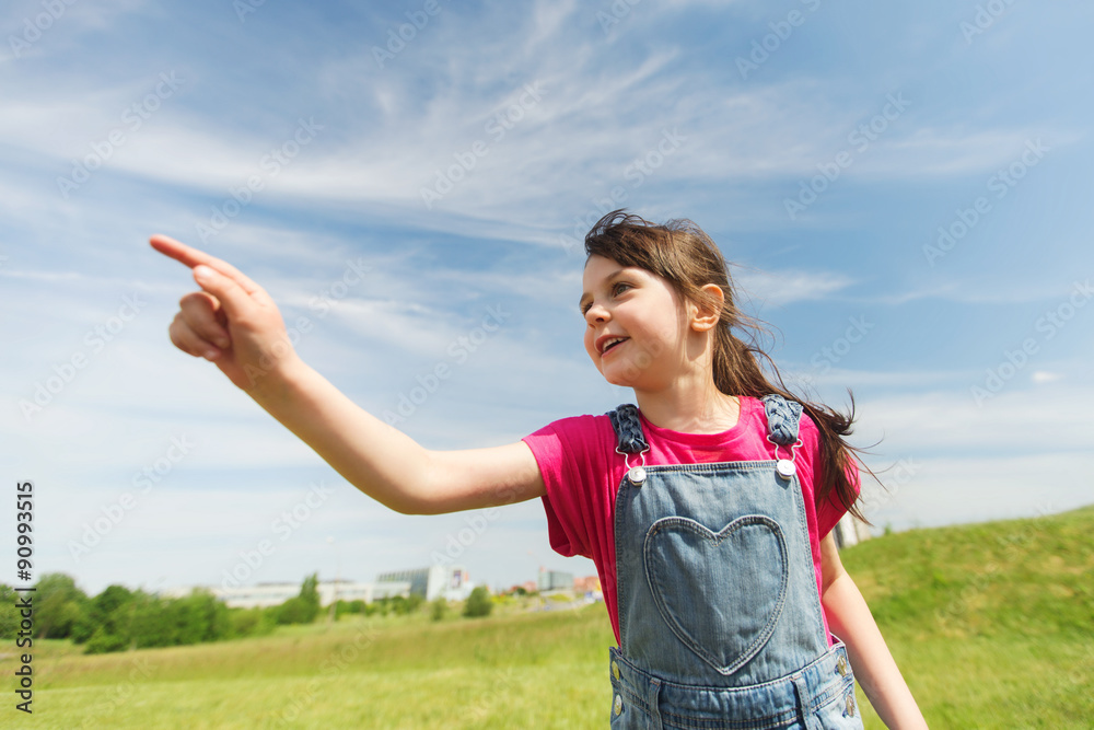 happy little girl pointing finger on summer field happy little girl pointing finger on summer field