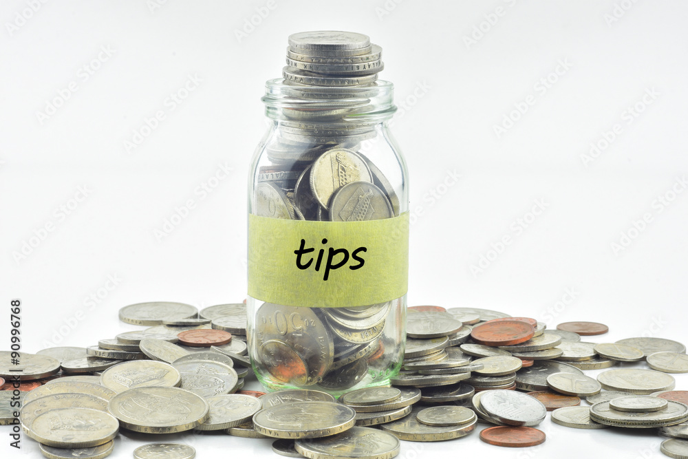 Isolated coins in jar with tips label - financial concept Isolated coins in jar with tips label - financial concept