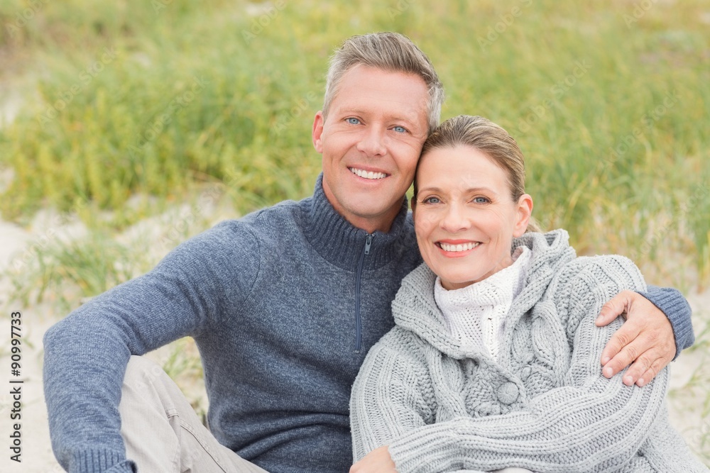 Smiling couple sitting on the sand Smiling couple sitting on the sand