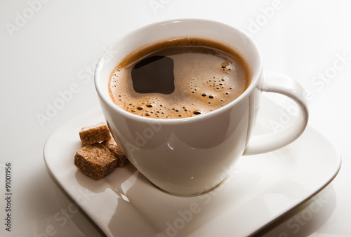 Cup of coffee and brown sugar cubes.