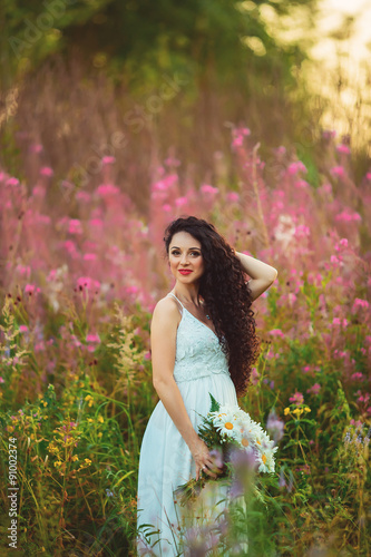 A young girl with a large bouquet of white flowers in a field at