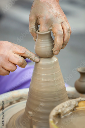 Hands making pottery on a wheel