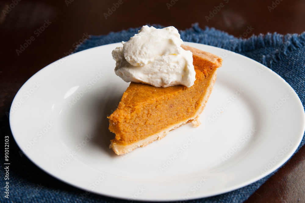 piece of pumpkin pie on a plate with a dollop of whipped cream piece of pumpkin pie on a plate with a dollop of whipped cream