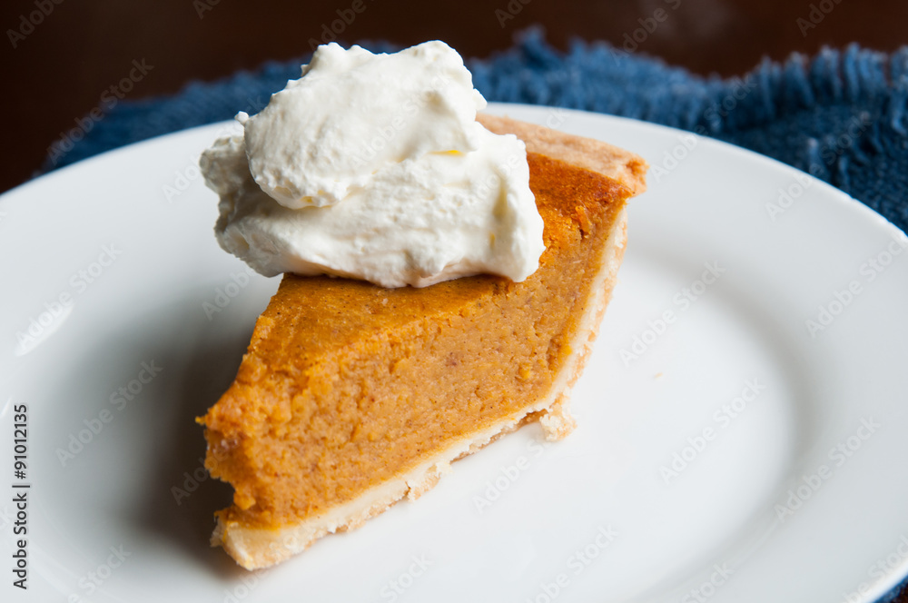 piece of pumpkin pie on a plate with a dollop of whipped cream piece of pumpkin pie on a plate with a dollop of whipped cream