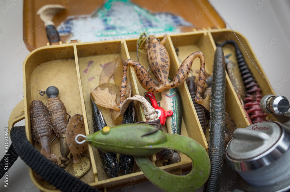 Rubber fishing lures and reel in small tackle box. Stock Photo