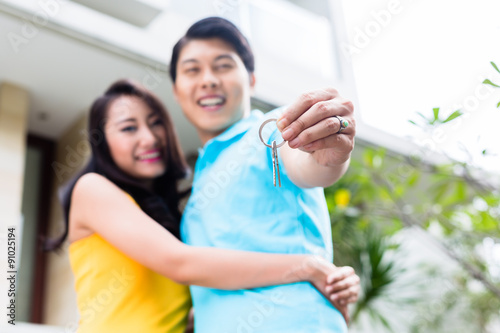 Chinese couple showing keys to their new home