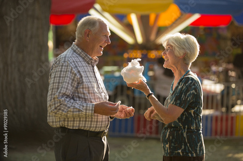 Happy fun couple sharing cotton candy snack at amusement park fun fair