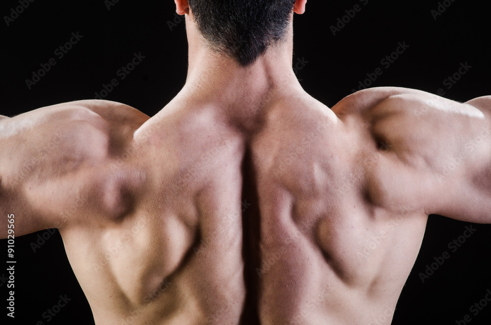 Muscular man posing in dark studio