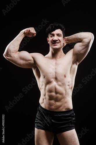 Muscular man posing in dark studio